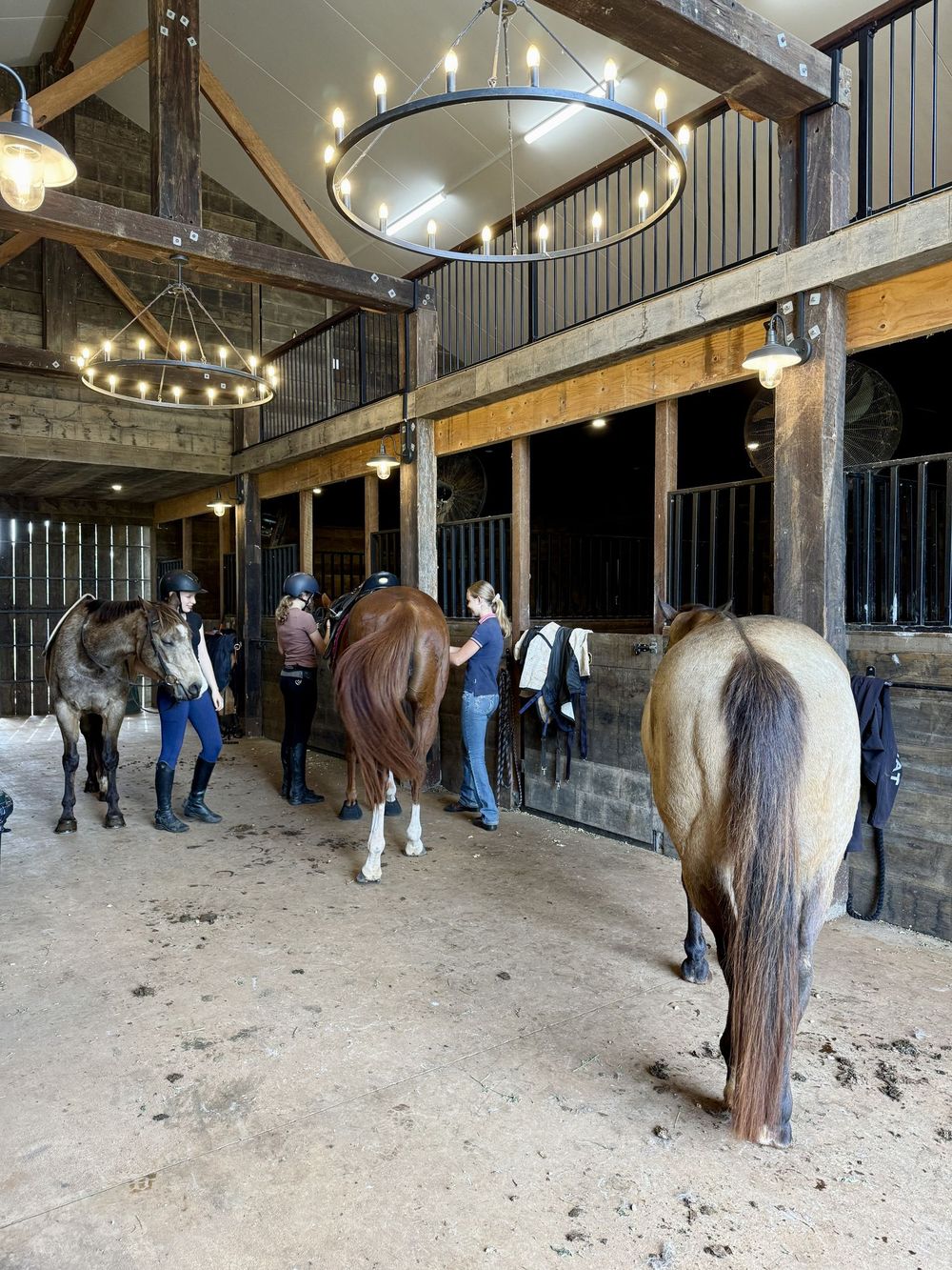 Riders tacking up in a timber barn aisle